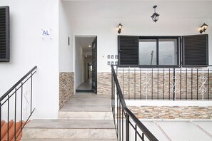Una scala con ringhiera in metallo, un muro in pietra e una finestra con persiane.