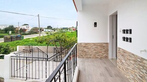 Ein Balkon mit Metallgeländer, eine Tür mit Lichtschalter und ein an der Wand befestigtes Telefon.