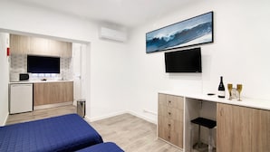 Een slaapkamer met twee bedden, een kitchenette, een televisie en een aan de muur bevestigd schilderij van een golf.