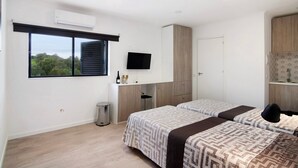 Un dormitorio con dos camas, televisión, escritorio y ventana con vistas.