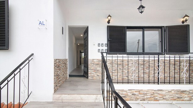 A staircase with a metal railing, a stone wall, and a window with shutters. - Apartment 'Sunset' with Shared Terrace, Wi-Fi and Air Conditioning (Moncarapacho)