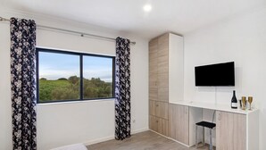 A bedroom with a bed, a desk with a TV, and a window with curtains. - Apartment 'Sunset' with Shared Terrace, Wi-Fi and Air Conditioning (Moncarapacho)