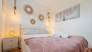 Een slaapkamer met een bed, nachtkastjes, wanddecoratie en een hanglamp.