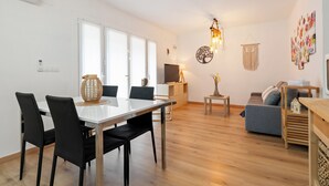 Een moderne woonkamer met een eethoek, houten vloeren en een groot raam.