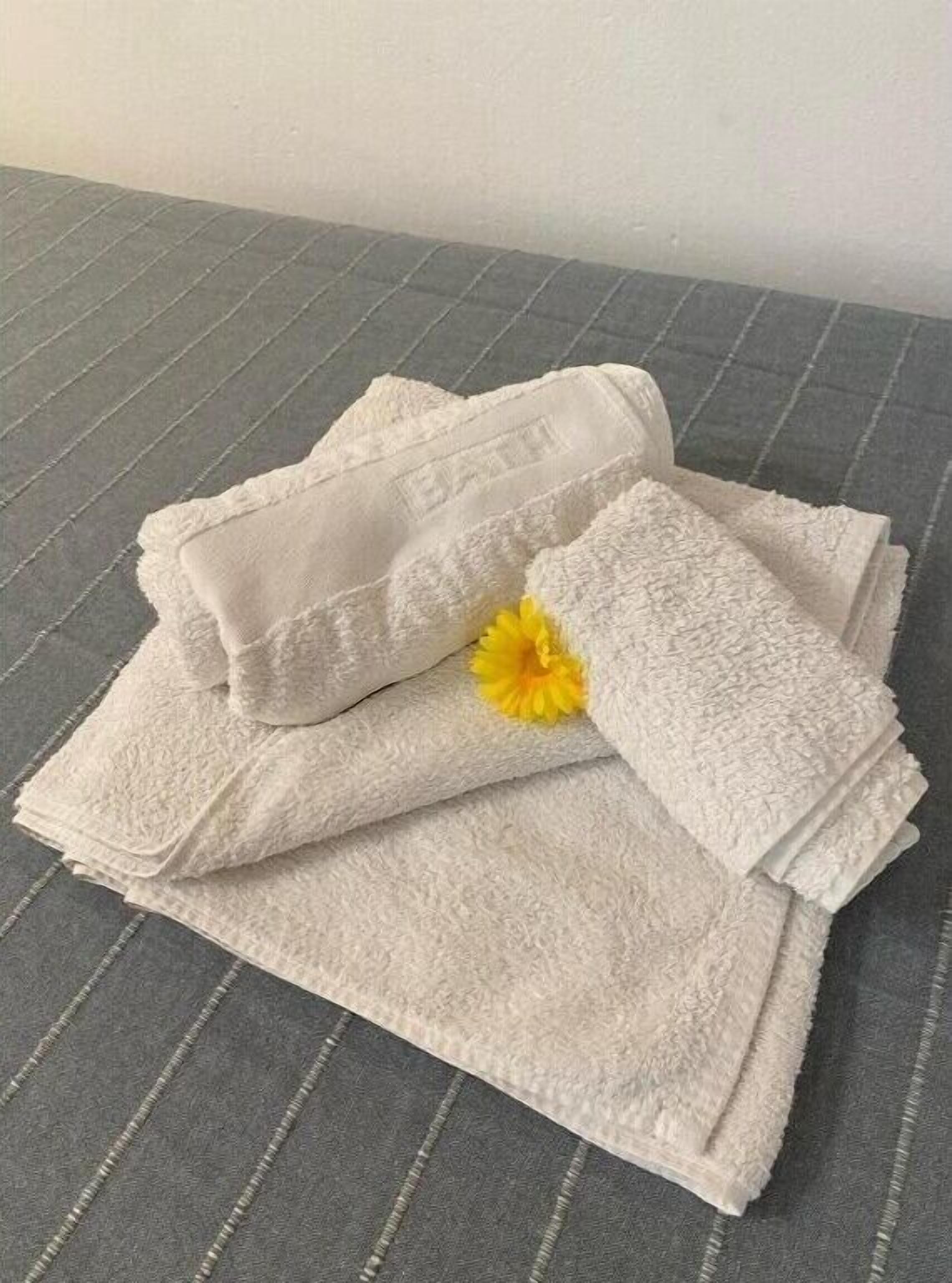 A stack of white towels with a yellow flower on a grey textured surface.