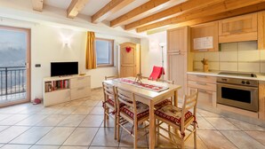 Een moderne keuken met houten kastjes, een eettafel met stoelen, een televisie en een balkon met uitzicht.