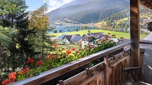 A wooden balcony with a view of a lake, mountains, and houses. - Holiday Apartment 'Appartements Egart 1' with Lake View, Balcony and Wi-Fi (Reschen)