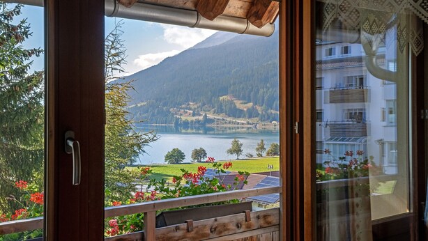 A view from a balcony with a wooden railing, a mountain in the background, and a body of water. - Holiday Apartment 'Appartements Egart 1' with Lake View, Balcony and Wi-Fi (Reschen)