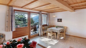 A room with a wooden ceiling, a dining table with chairs, a bench, a window with curtains, and a potted plant. - Holiday Apartment 'Appartements Egart 1' with Lake View, Balcony and Wi-Fi (Reschen)