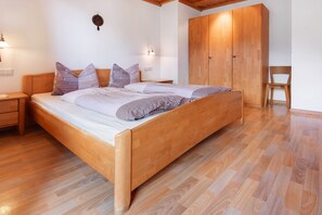 A bedroom with a wooden bed, nightstands, a wardrobe, and a chair.