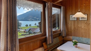 A wooden cabin with a view of a lake and mountains, a table with a flower, and a bench. - Holiday Apartment 'Appartements Egart 2' with Lake View, Balcony and Wi-Fi (Reschen)