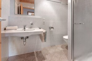A bathroom with a sink, mirror, towel rack, toilet, and a door.