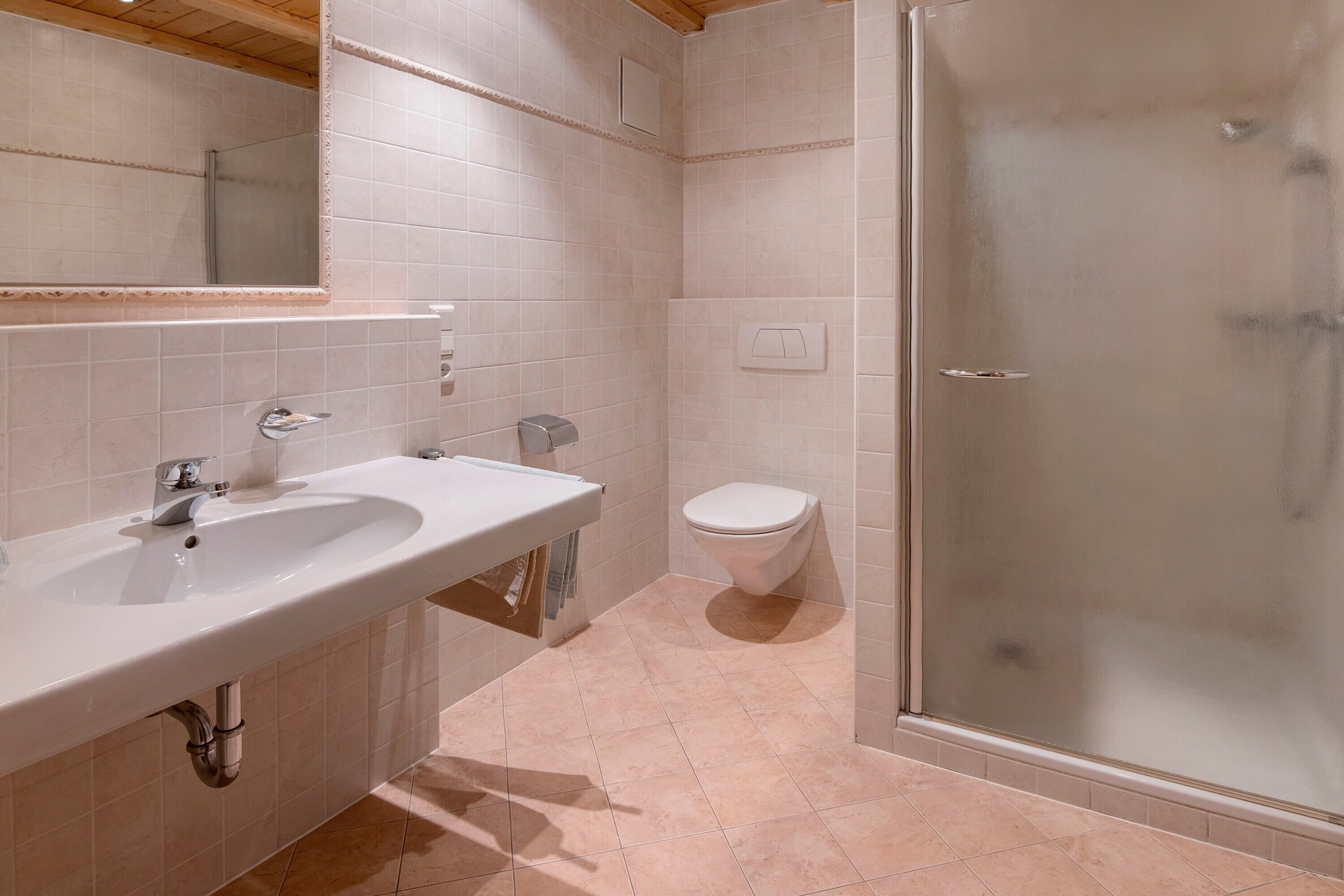 A bathroom with a sink, toilet, and glass shower enclosure.