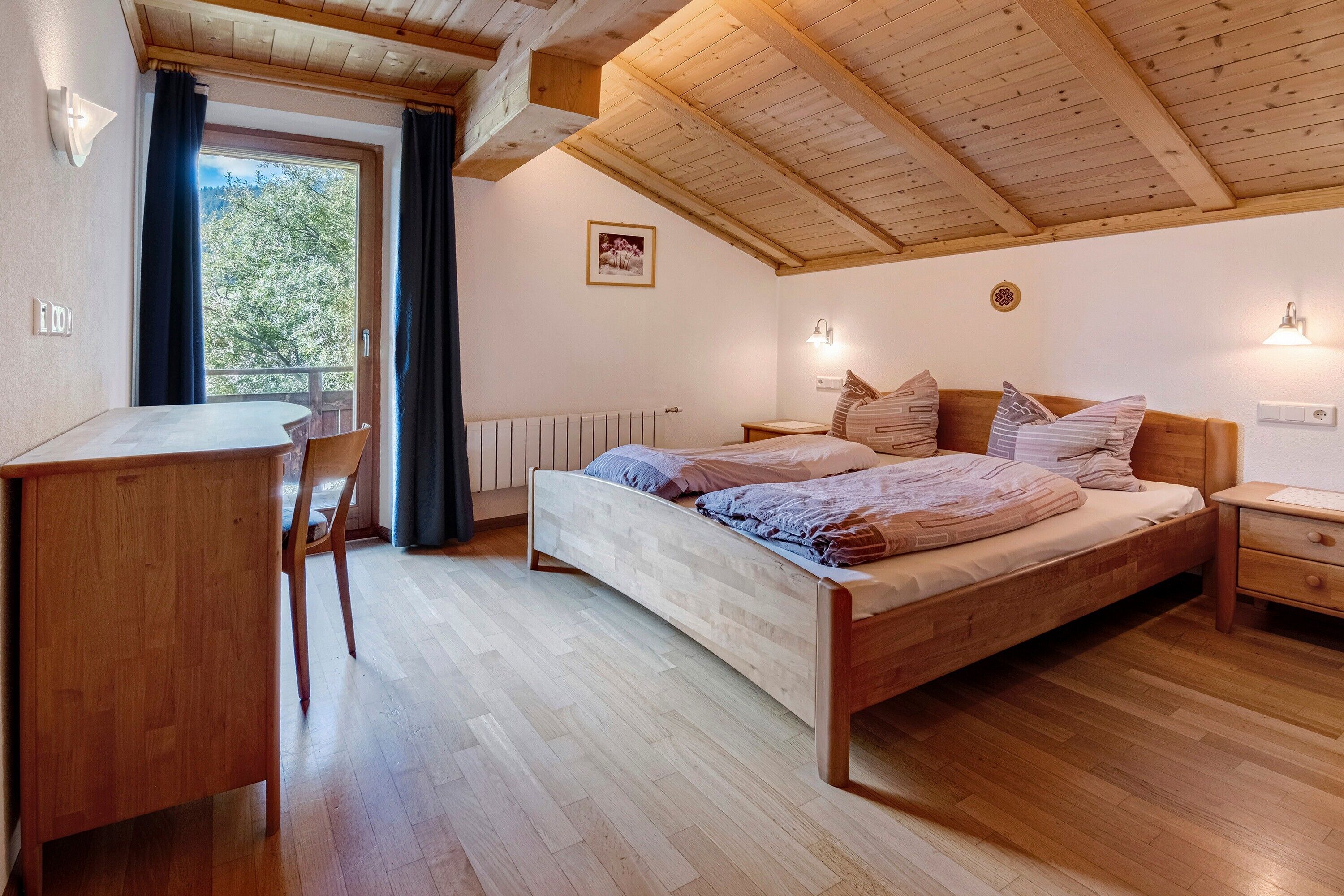 A bedroom with a wooden bed, a desk, and a chair.