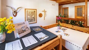 Un espace repas avec une table en bois, des cartes de menu, un tableau encadré et une tête d’animal fixée au mur.