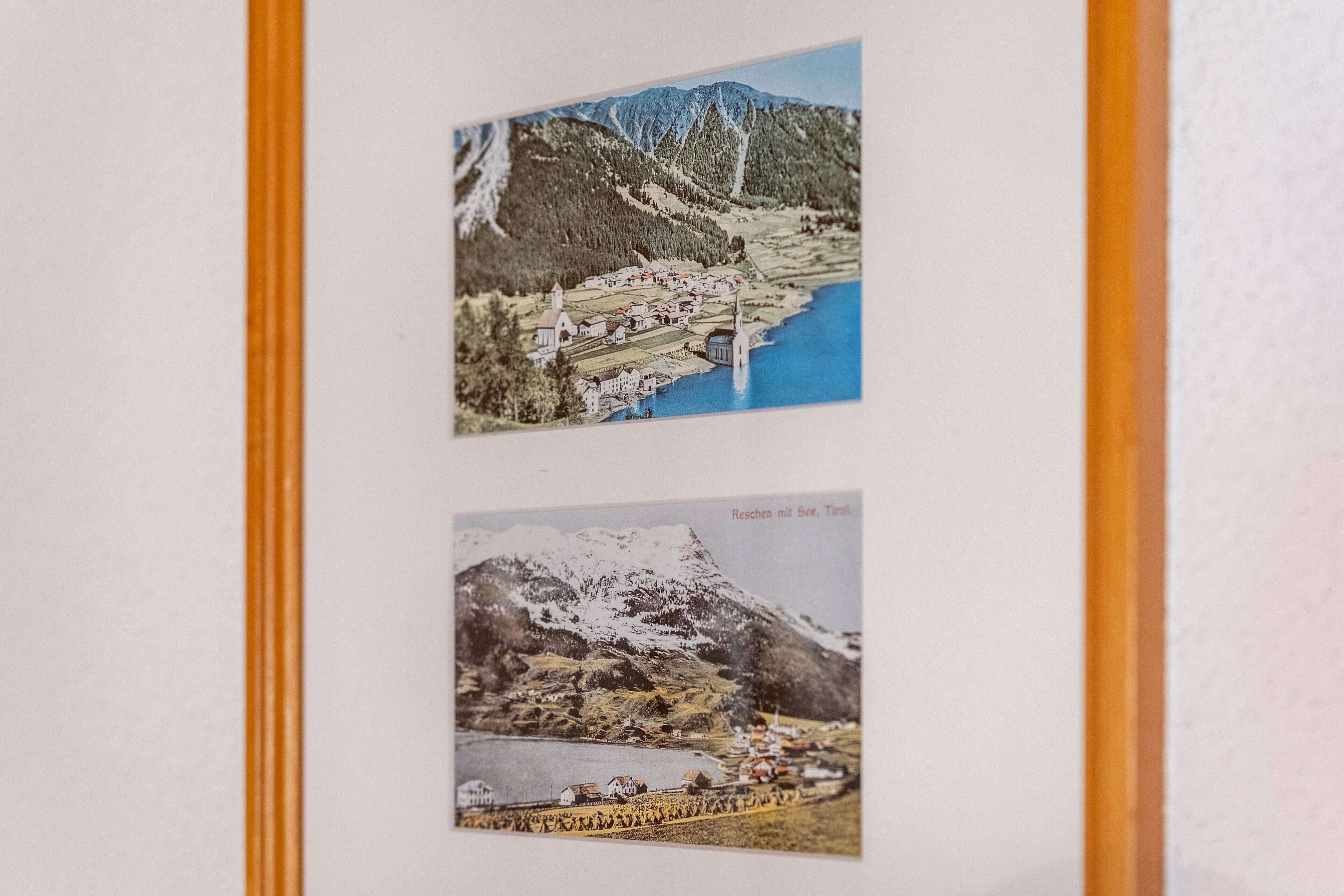 Zwei gerahmte Fotografien von Berglandschaften mit Gewässern und Gebäuden.