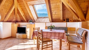 Een houten interieur met een televisie, tafel, stoelen en een bank.