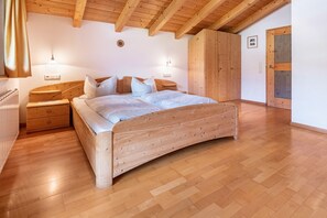 A bedroom with a wooden bed, bedside tables, a wardrobe, and a wooden ceiling. - Holiday Apartment 'Mansardenwohnung Egart' with Lake View, Balcony and Wi-Fi (Reschen)