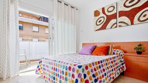 Quarto com uma cama, mesa de cabeceira, planta em vaso e vista de um edifício.