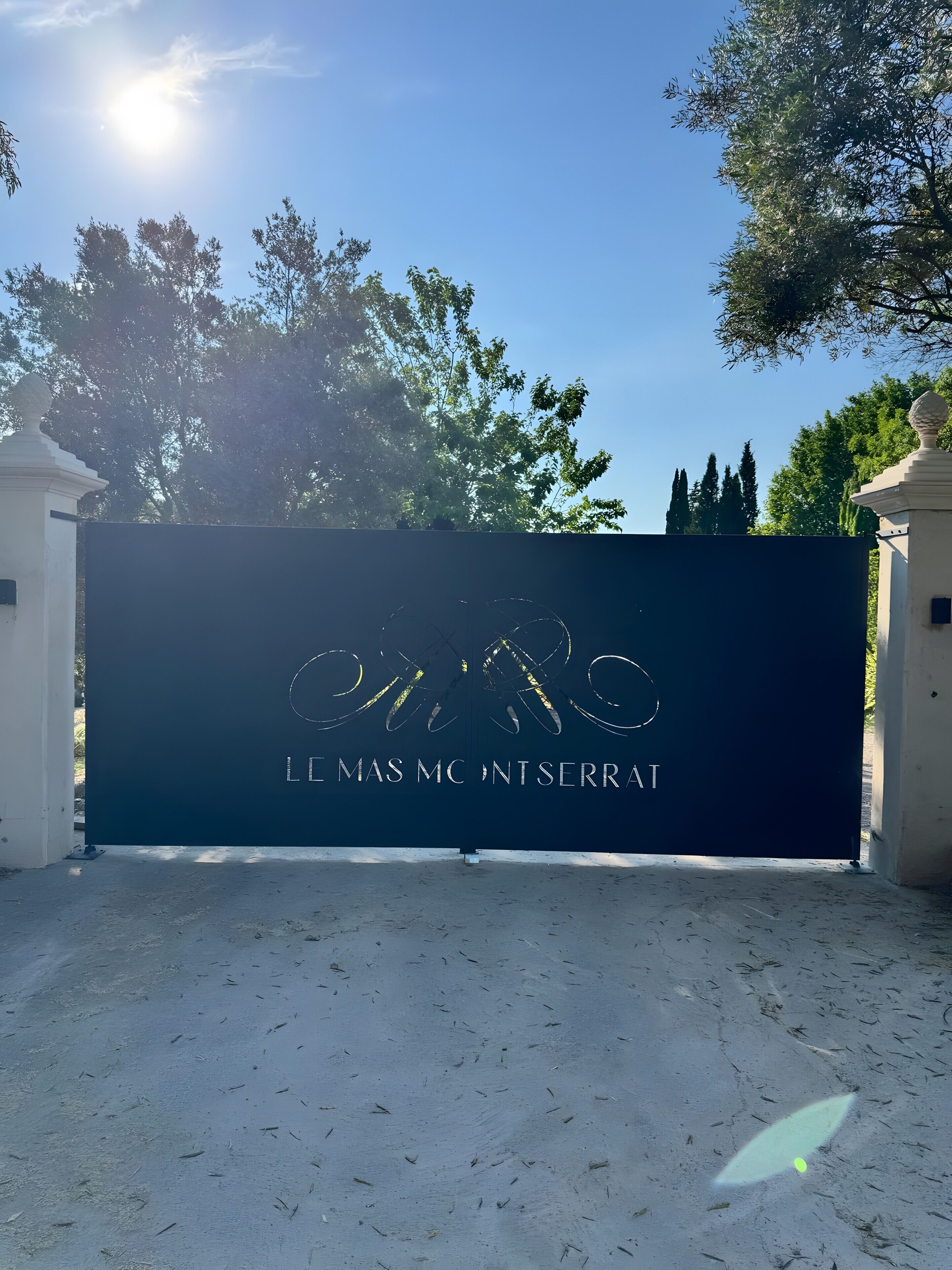 A gated entrance with a sign that reads 'LE MAS MC NT SERRAT.'