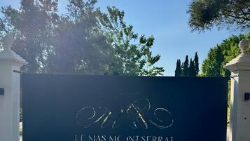 A gated entrance with a sign that reads 'LE MAS MC NT SERRAT.'