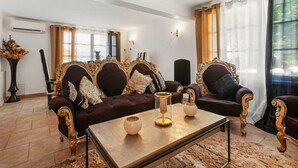 Ein Wohnzimmer mit einem dunkelroten Sofa, verzierten goldfarbenen Möbeln und einem Couchtisch mit Dekoration.