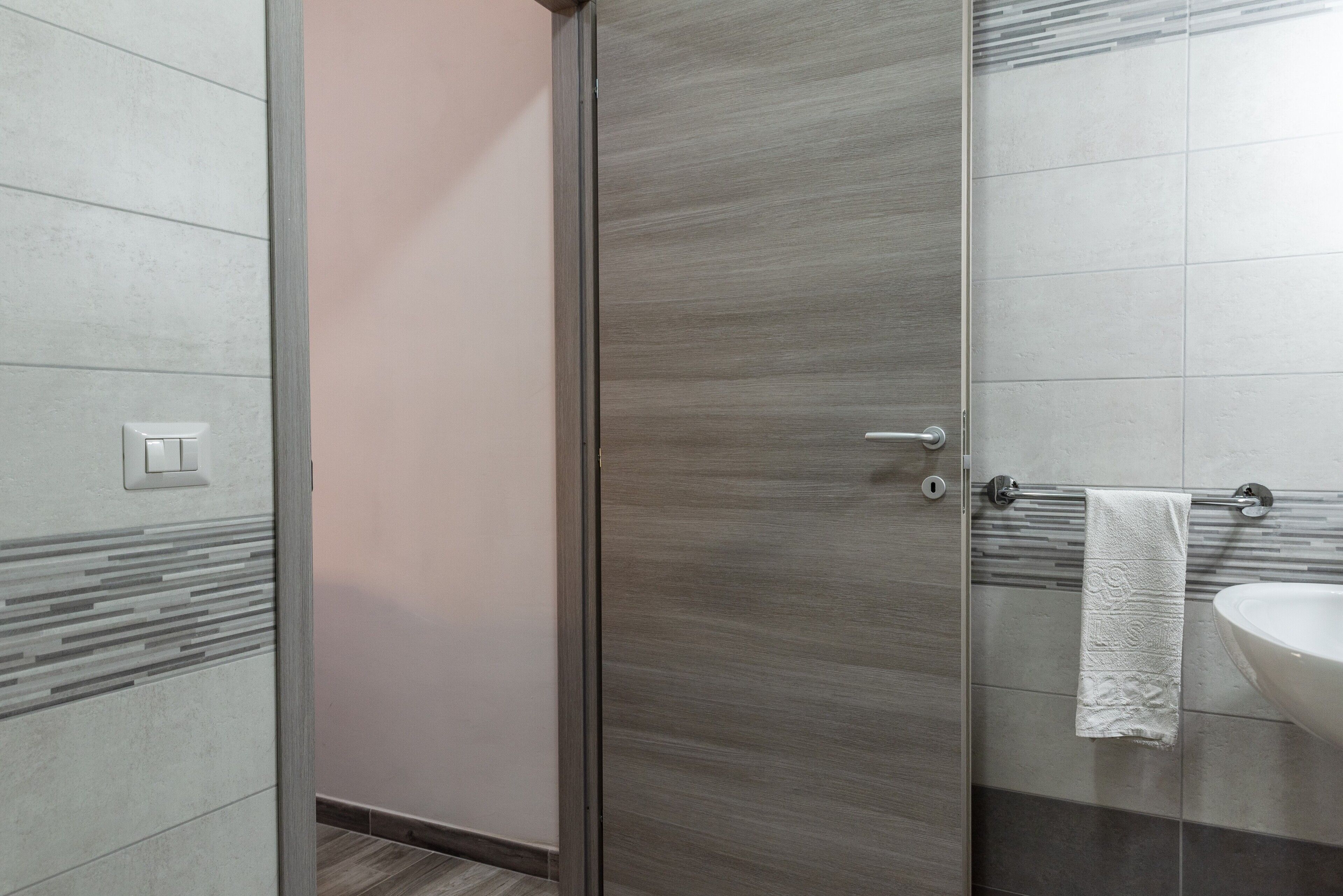 A bathroom with a glass shower door, a sink, and a towel hanging on the wall.