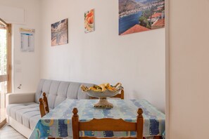 A dining area with a table covered by a patterned tablecloth, a wooden chair, and a decorative bowl on the table.