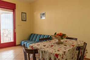 Un comedor con una mesa dispuesta para dos, un sofá y una ventana con vistas.