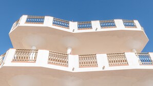 Ein mehrstöckiges Gebäude mit Balkonen, blauem Himmel und einer weißen Fassade.