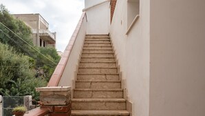 Eine Treppe führt zu einem Gebäude mit weißer Fassade und einem roten Ziegeldach.