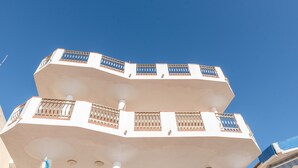 A multi-story building with balconies and a clear blue sky.