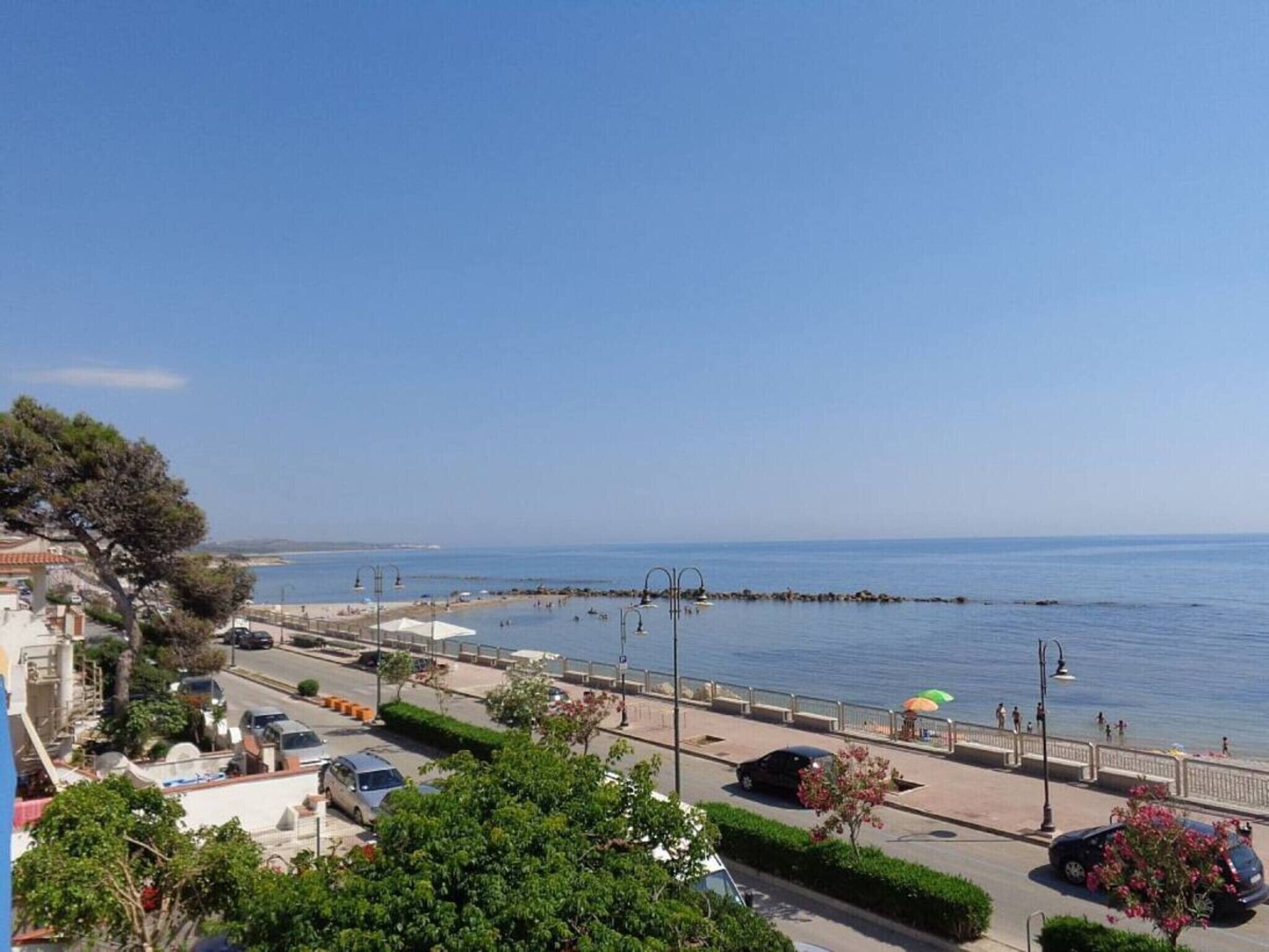 Eine Küstenstraße mit Blick auf das Meer, geparkten Autos und einem Fußweg.