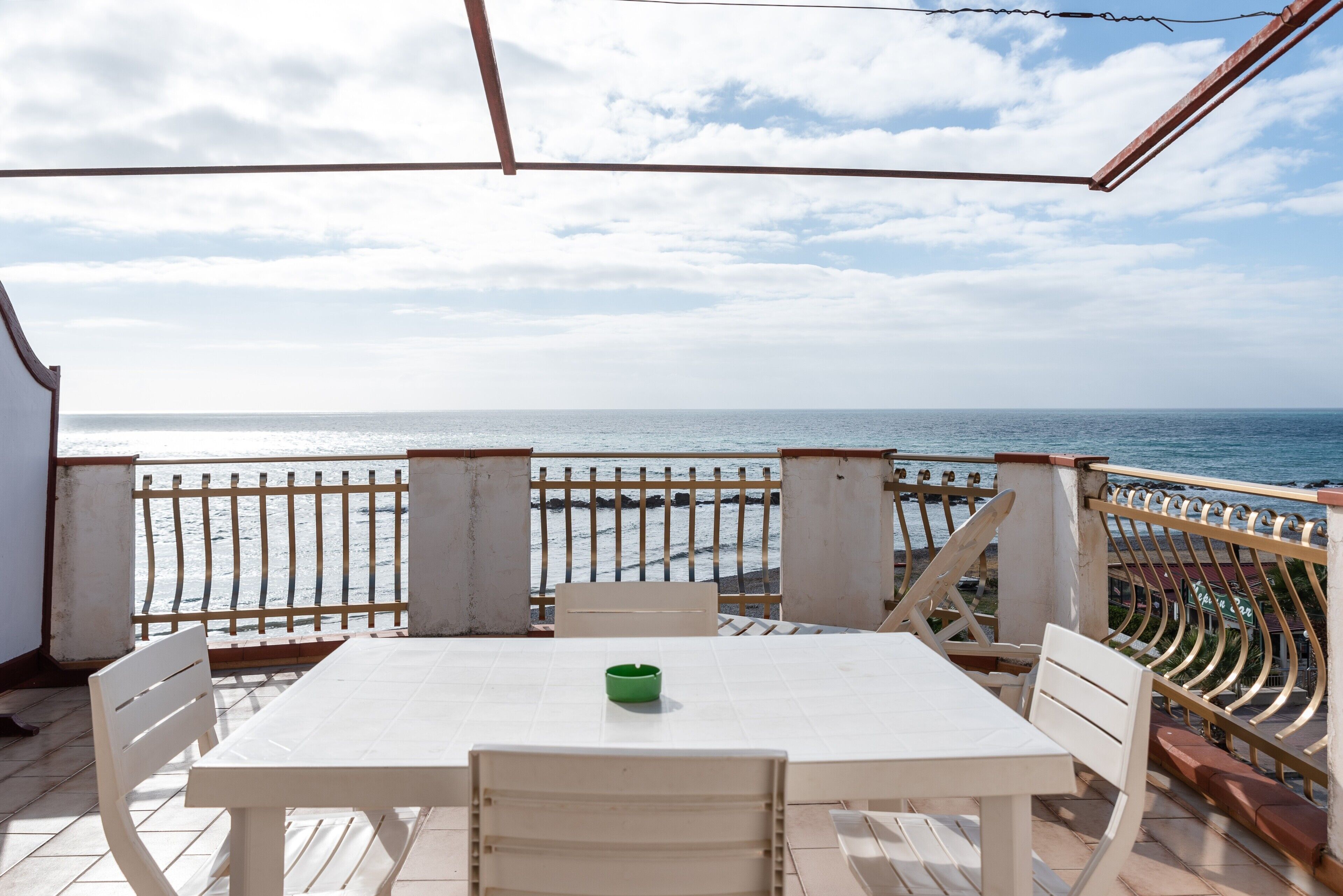 Terraço com mesa e cadeiras, com vista para a praia.