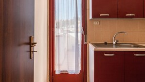 A kitchen with a sink, cabinets, and a window with a curtain.