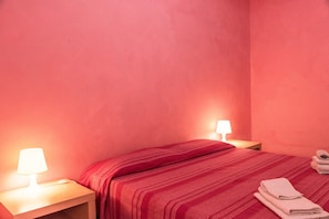 Une chambre avec un lit, deux lampes de chevet et une pile de serviettes sur le lit.