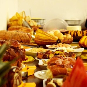 A buffet with various dishes including bread, pastries, and meats. - Pousada Pé da Serra  (Lindoia)
