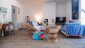 Un salon moderne comprenant un canapé, deux fauteuils en osier, une table basse et un téléviseur.