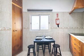 A kitchen with a dining table, four stools, a window, and a fire safety sign.
