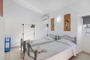 A hotel room with two beds, a drying rack, a blue shelf, and a window with a view. - Apartment 'Casa Da Vila Nº4' with Wi-Fi and Air Conditioning (São Brás de Alportel)
