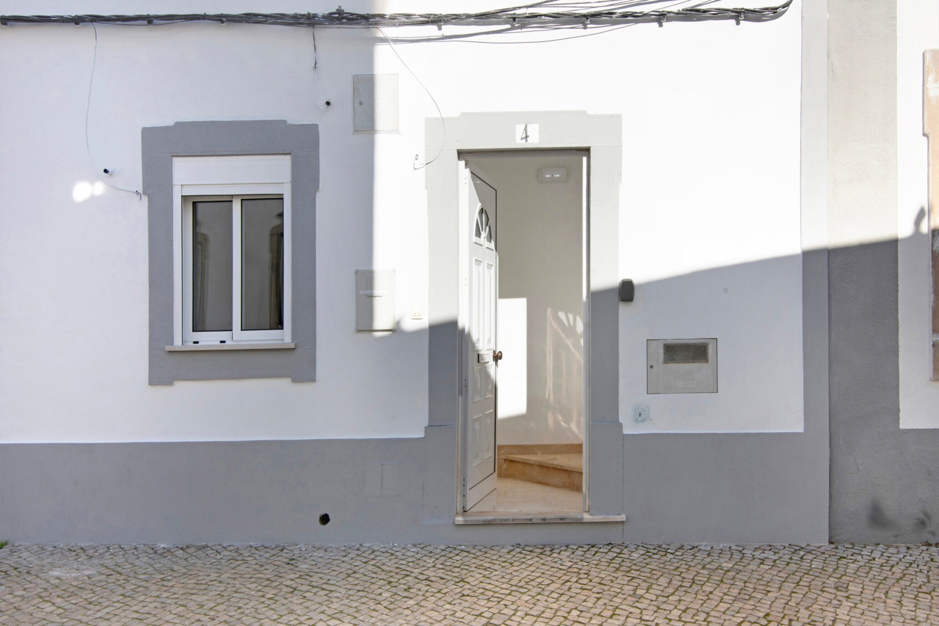 Um edifício com uma porta marcada '4', uma janela e uma pequena janela quadrada na parede.