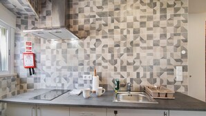 Eine Küche mit ornamental gestalteter Spritzschutzleiste, einer Edelstahlspüle und einer Arbeitsplatte mit Schneidebrett und Tassen.