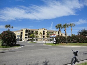 A multi-story hotel with a central courtyard, palm trees, and a bicycle parked in front.