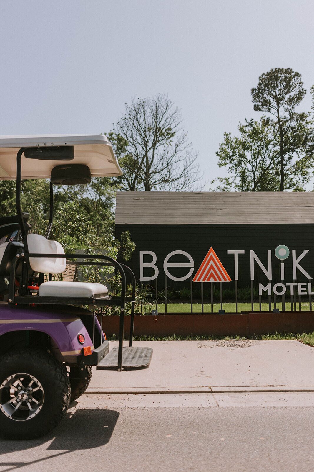 A golf cart parked in front of a motel sign with a triangular logo.