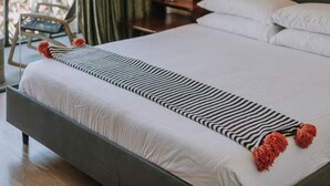 Ein modernes Schlafzimmer mit einem großen Bett, einer Pendelleuchte und Blick auf Grünflächen.