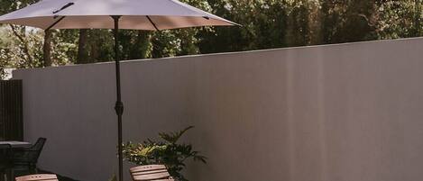 A swimming pool with two wooden lounge chairs and a white umbrella.