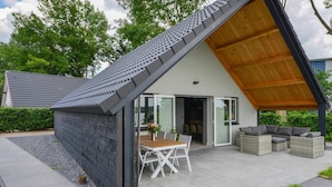 A modern house with a sloped roof, a patio with a table and chairs, and a covered seating area. - Nice home in Kerkdriel with WiFi (Kerkdriel)