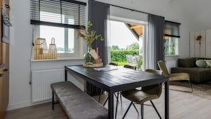 A modern kitchen with a dining area, featuring a large window with blinds, a bench, and a table with chairs. - Nice home in Kerkdriel with WiFi (Kerkdriel)