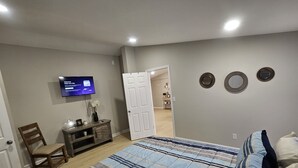 Ein Schlafzimmer mit einem Bett, einem Fernseher, einem Schreibtisch und einem Stuhl.