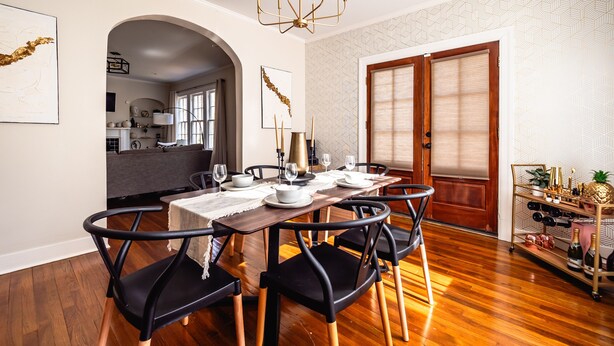 A dining area with a wooden table set for four, black chairs, and a chandelier. - NEW! Stylish and Modern Home In the Heart of the Popular Fondren District (Jackson)